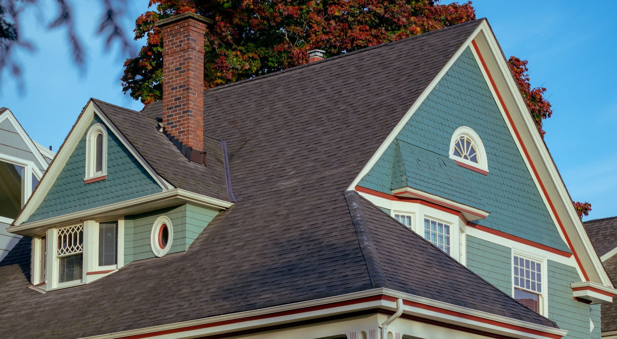 A shingled Queen Anne house in low autumn sun, under a clear sky
